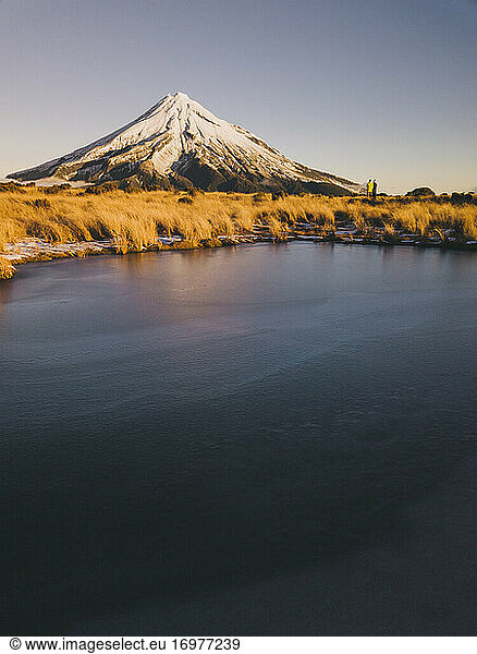 Young couple in the distance enjoying sunset time at Mt Taranaki  New Zealand