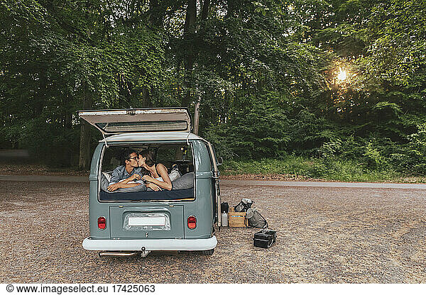 Young couple kissing each other in camping van during vacation
