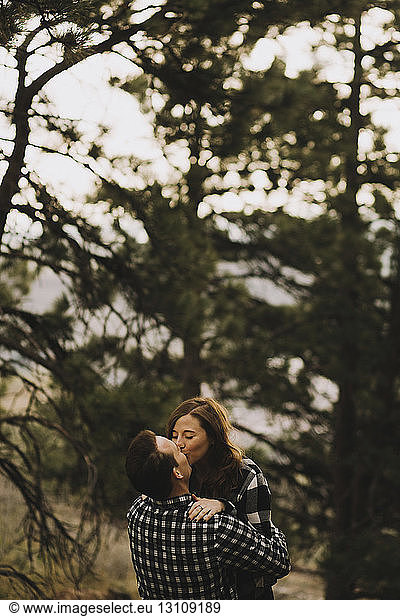 Young couple kissing on mouth against trees