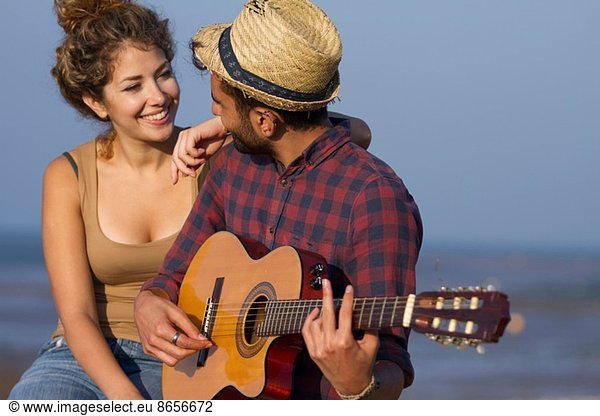 Young couple  man playing guitar