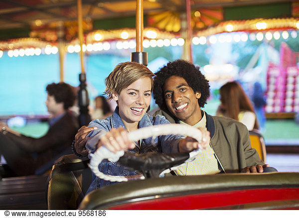 Young couple on bumper car ride in amusement park