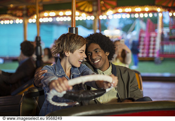 Young couple on bumper car ride in amusement park