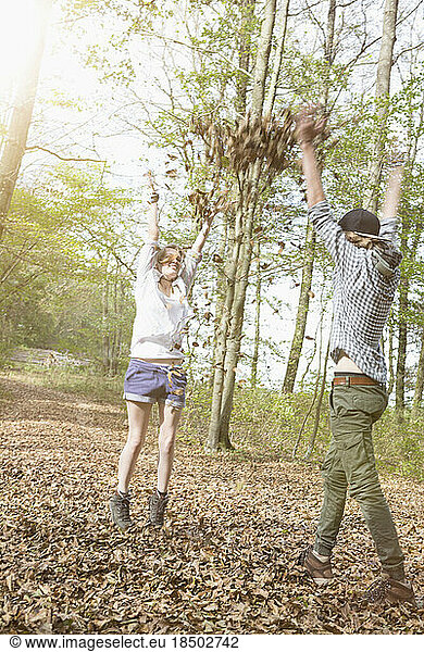 Young couple playing with autumn leaves in a forest  Bavaria  Germany