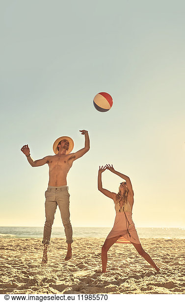 Young couple playing with beach ball on sunny summer beach