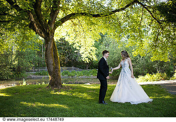 Young couple prepare to dance under large tree in nature.