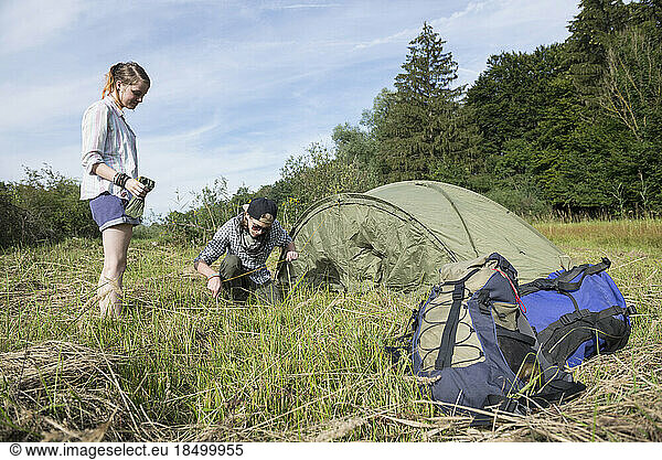 Young couple setting up tent in a forest  Bavaria  Germany