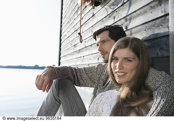 Young couple sitting boathouse wall portrait