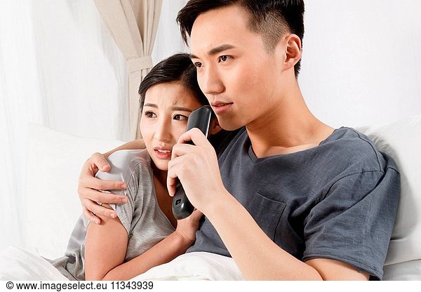 Young couple sitting on the bed watching TV