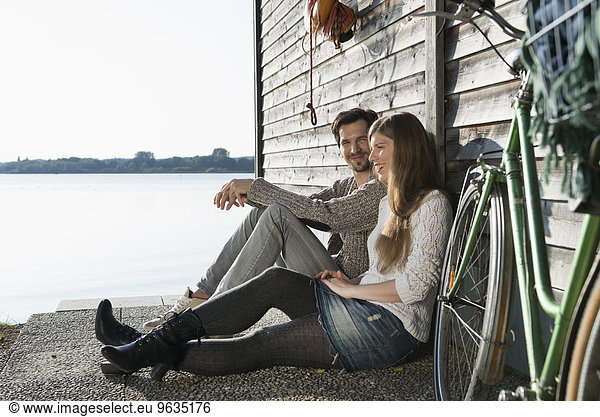 Young couple sitting relaxing lake boathouse