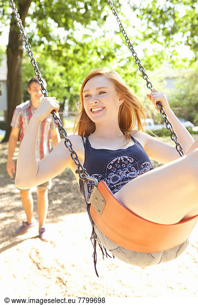 Young couple spend time on the swingset in park on a warm summer day in Portland  Oregon  USA