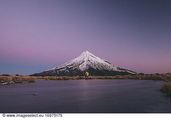 Young couple standing at the foot of Mt Taranaki  by a frozen lake  New Zealand