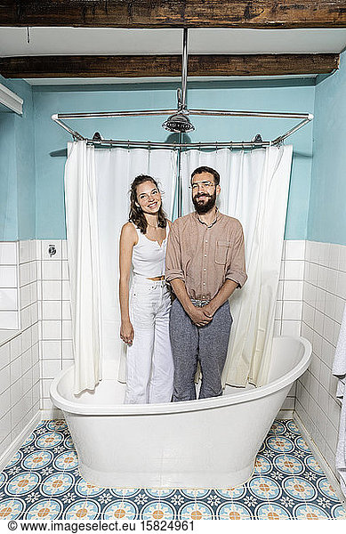 Young couple standing in bath tub  laughing