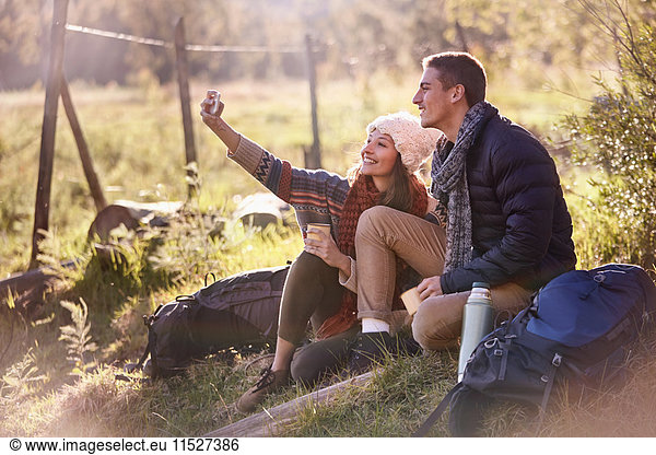 Young couple taking a break from hiking  taking selfie with camera phone