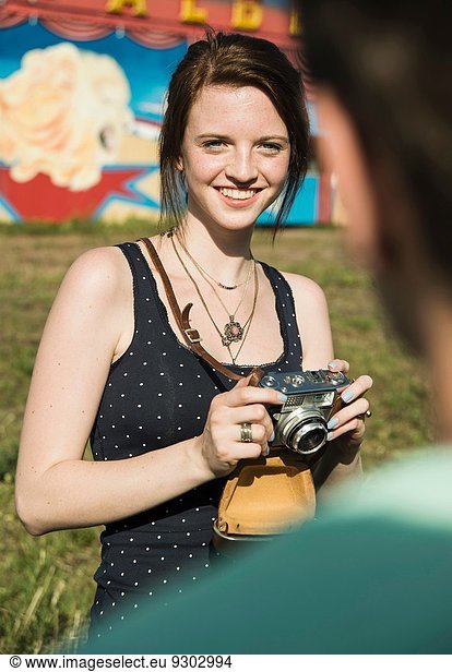 Young couple taking photographs on SLR camera at funfair