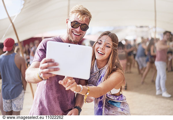 Young couple taking selfie with digital tablet at music festival