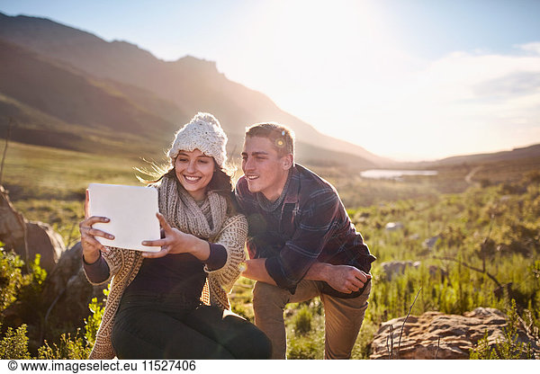 Young couple taking selfie with digital tablet camera in sunny valley