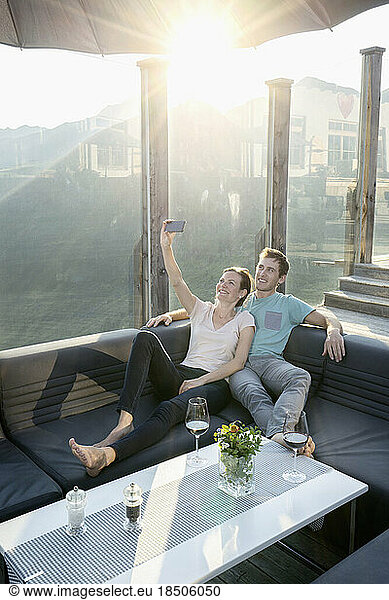 Young couple taking selfie with smartphone on terrace and smiling  Zillertal  Tyrol  Austria