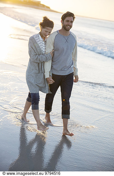 Young couple walking on beach in evening sun