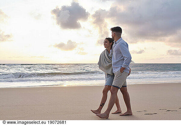 Young couple walking on sand near sea at beach