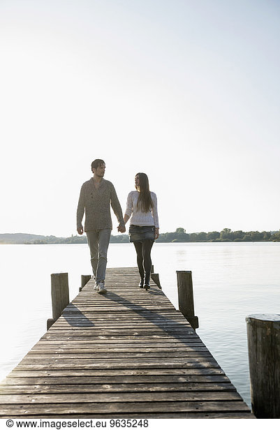 Young couple walking on wooden jetty