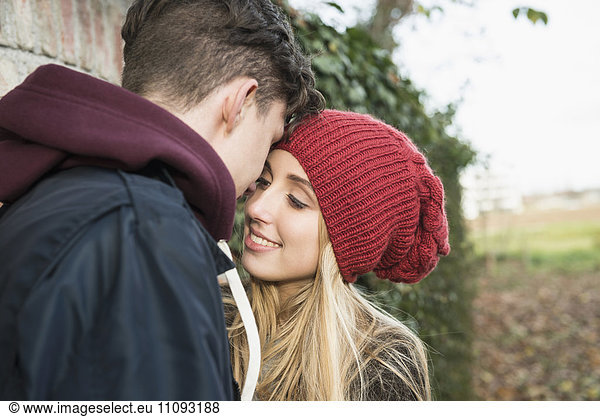 Young couple whispering something against brick wall