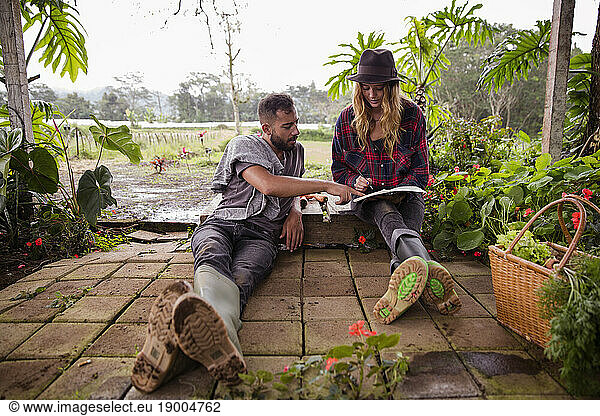 Young couple with diary sitting in garden