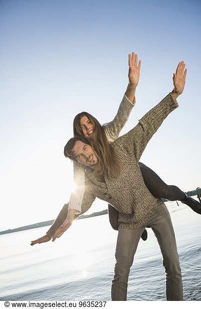 Young couple woman riding piggyback sunset