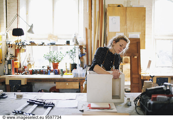 Young craftswoman checking component in pipe organ workshop