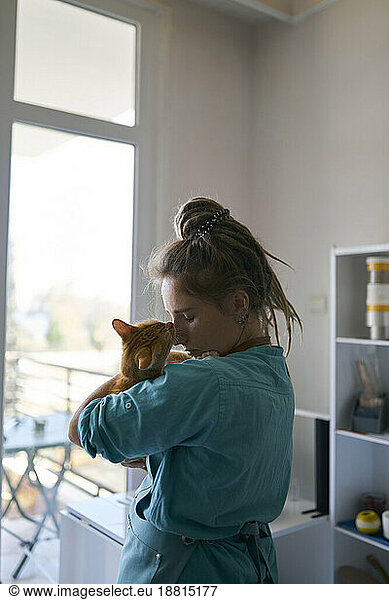 Young craftswoman embracing cat at workshop