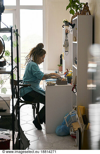 Young craftswoman working at workbench at home