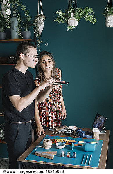 Young creative couple taking smartphone picture of decoration on table