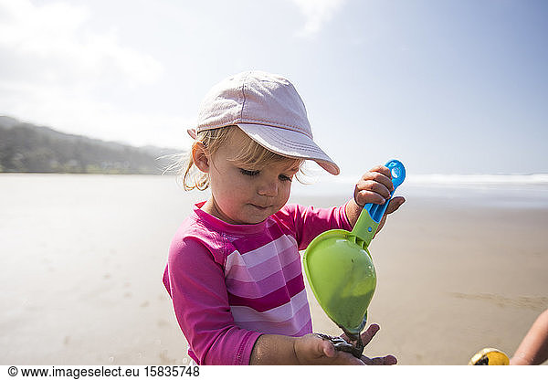 Young cute girl using shovel at the beach.