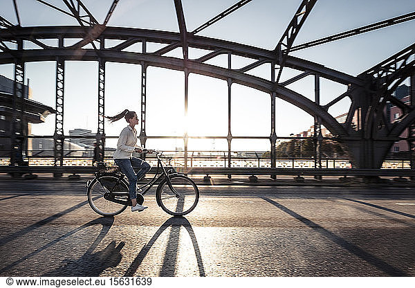 Young cyclist on a bridge at sunset