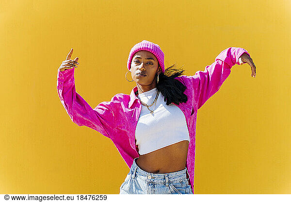 Young dancer dancing in front of yellow wall