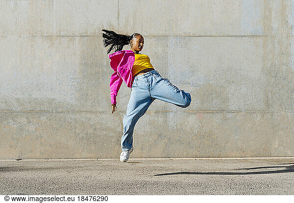 Young dancer hip hop dancing in front of wall