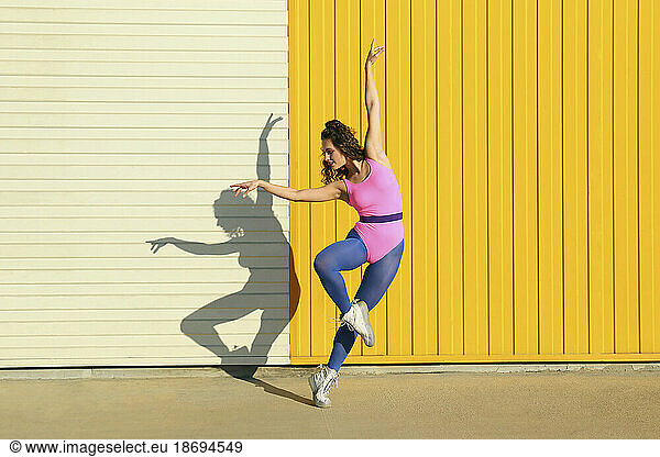 Young dancer showing ballet moves in front of yellow wall