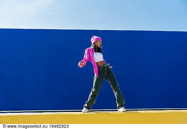 Young dancer wearing knit hat dancing on wall