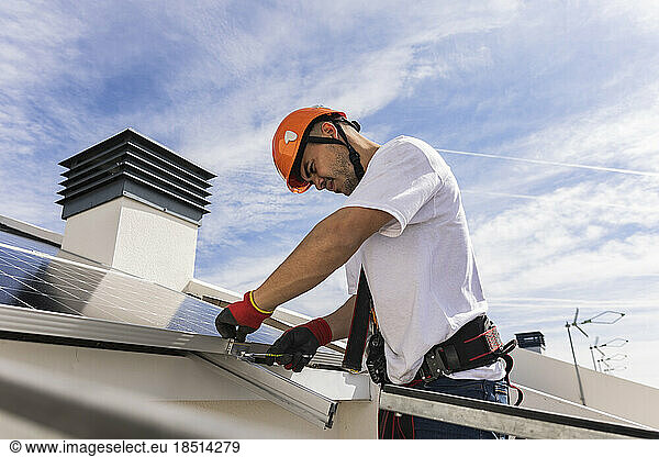 Young engineer wearing hardhat installing solar panels