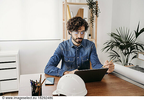 Young engineer working on laptop sitting at desk in office
