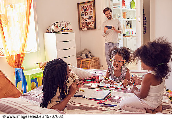 Young family coloring on bed