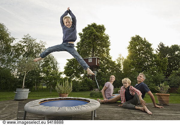 Young family garden boy jumping trampoline