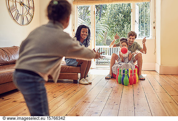 Young family playing bowling in living room