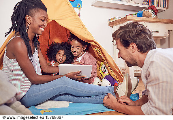 Young family using digital tablet on teepee