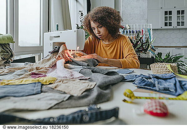 Young fashion designer sewing clothes in workshop