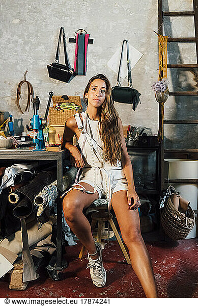 Young fashion designer sitting at workbench