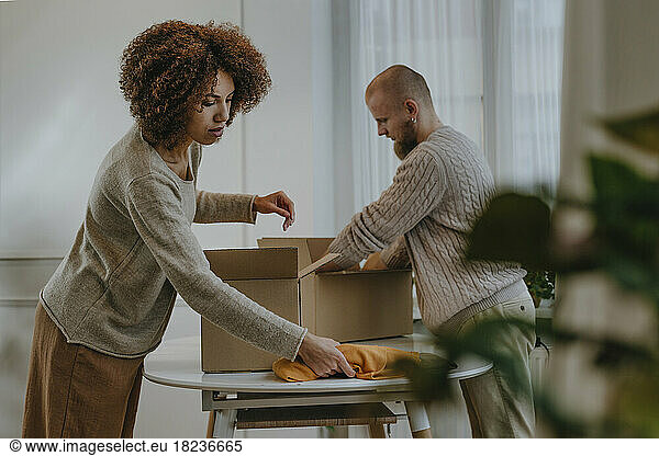 Young fashion designer with colleague packing clothes in box