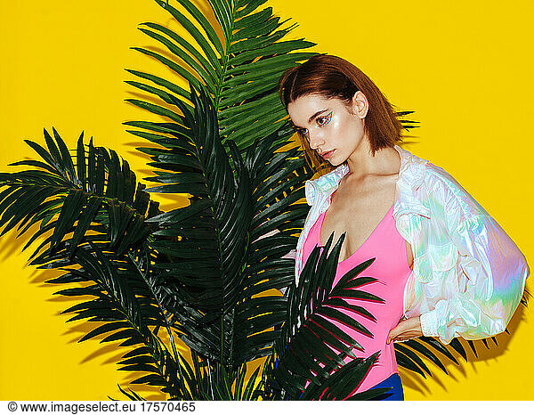 young fashion female model in iridescent jacket isolated on yellow