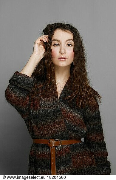 Young fashion model in knitted woolen coat posing. perfect healthy skin. red lips