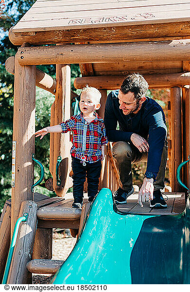 Young Father Plays with Toddler Boy on Wooden Playground