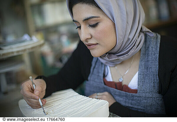 Young female artist in hijab working in art studio